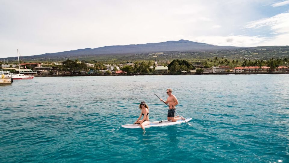 a couple on a paddle board in hawaii ocean