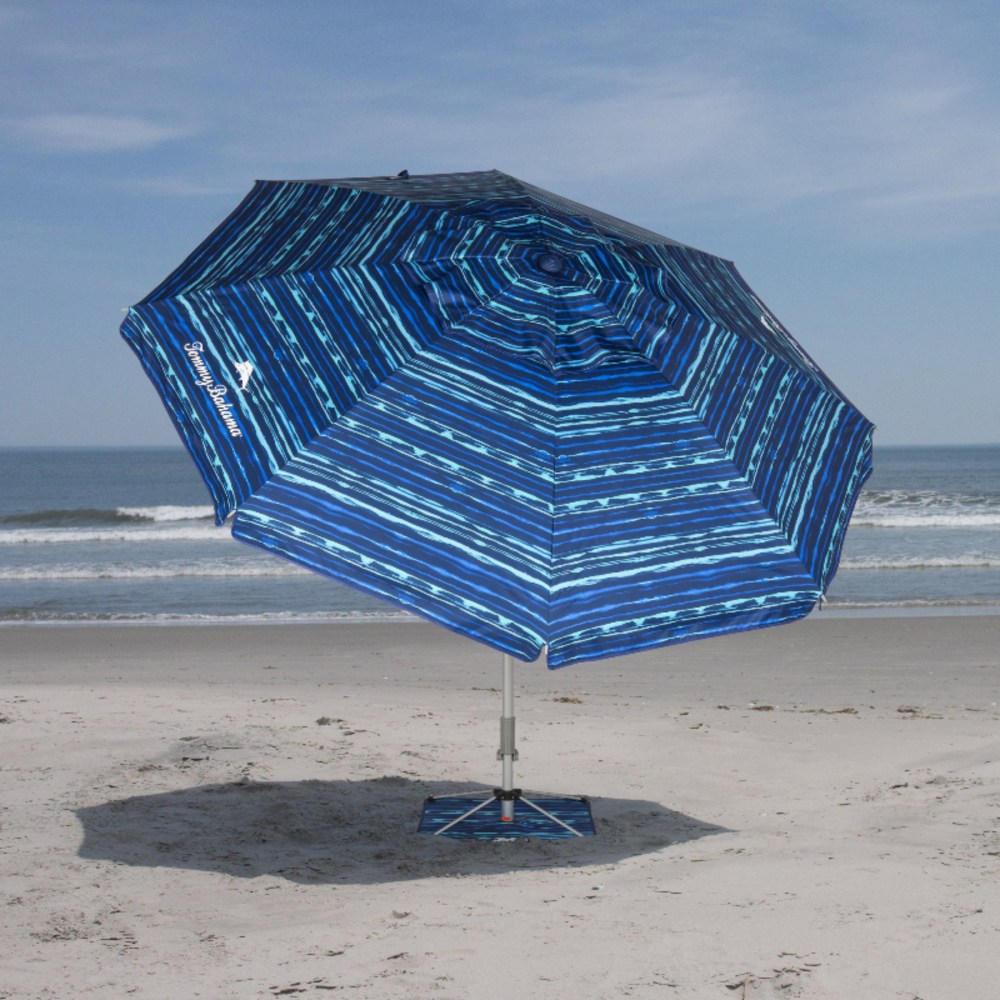 Blue beach umbrella on sandy shore with ocean backdrop.