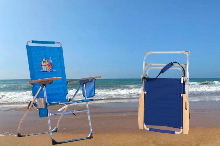 Two beach chairs on sand by the sea under a clear sky.