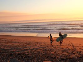 a man carrying a surfboard on top of a sandy beach