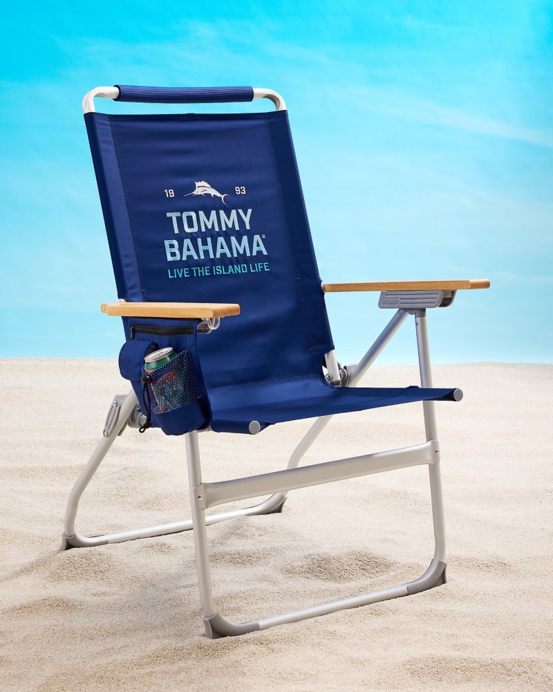 Blue Tommy Bahama beach chair on sand with a drink holder.