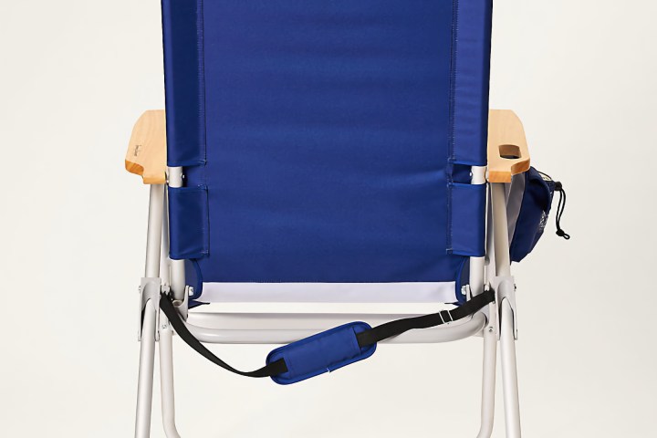 Back view of a blue folding beach chair with armrests and a shoulder strap.