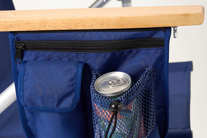 Blue chair armrest with pockets, holding a can and other items.